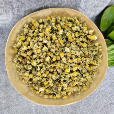 Dried chamomile flowers in a wooden bowl